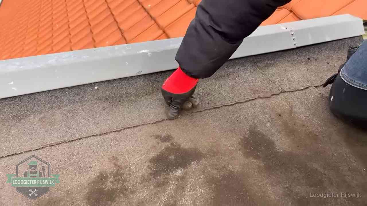 Lekkage bij de naad van een plat dak in Rijswijk Vakman wijst een naad met vochtplekken aan op een bitumen plat dak in Rijswijk