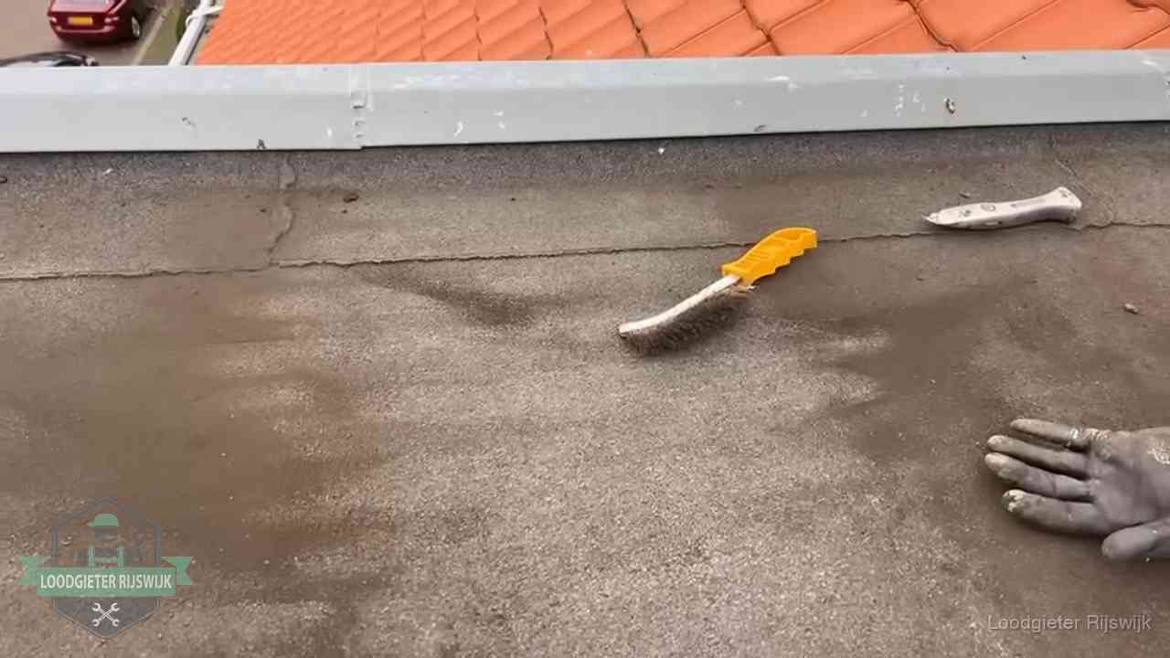 Kosten van daklekkage-reparatie in Rijswijk Dakdekker bereidt een bitumen plat dak voor op reparatie bij de daktrim in Rijswijk