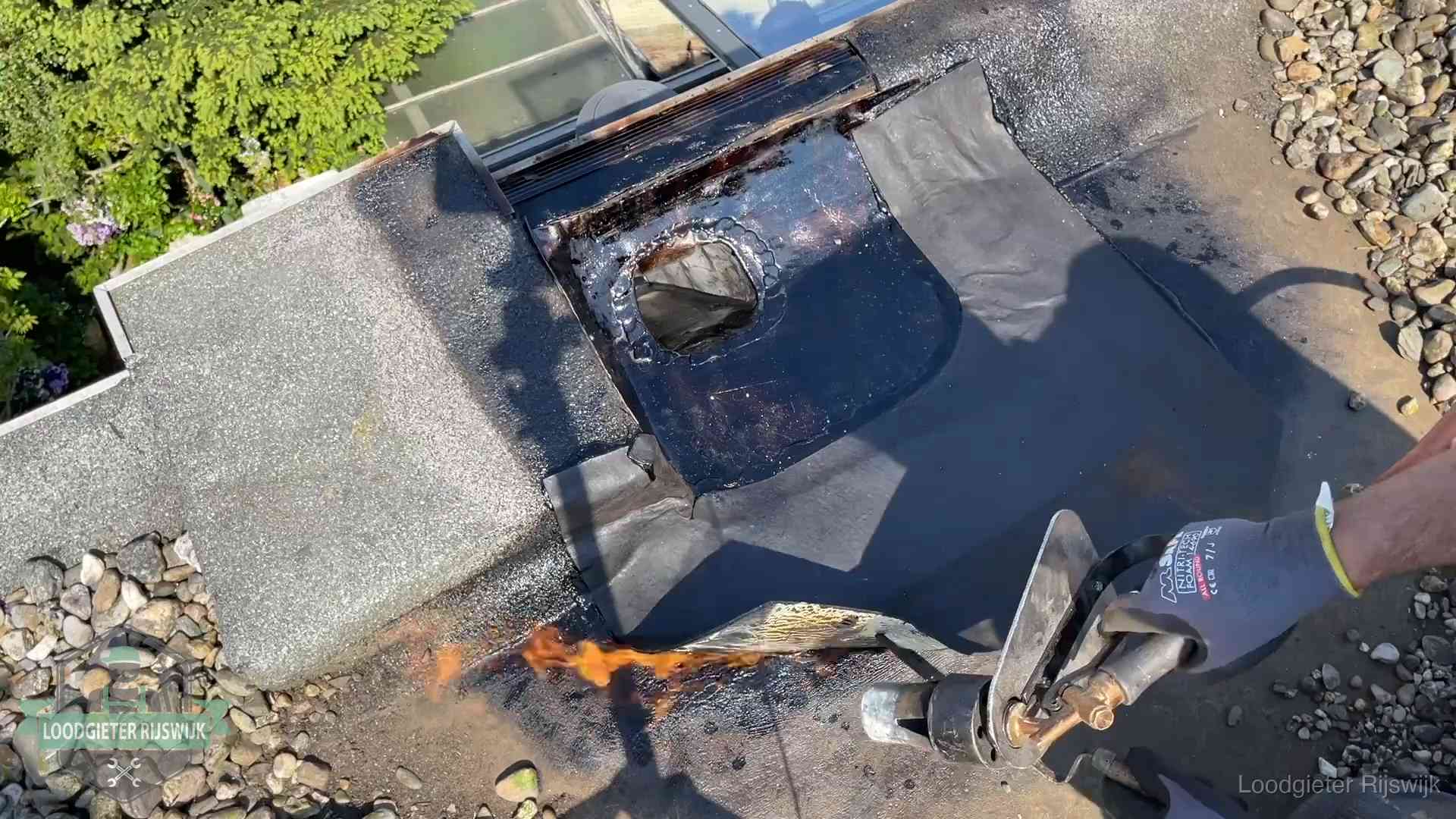 Daklekkage repareren in Rijswijk Dakdekker brandt bitumen rond een doorvoer tijdens een daklekkage-reparatie in Rijswijk