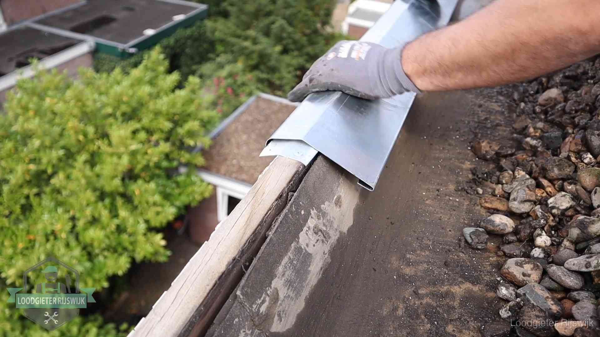 Daklekkage per wijk in Rijswijk Dakdekker plaatst een zinken deklijst op een dakrand met uitzicht over een woonwijk in Rijswijk