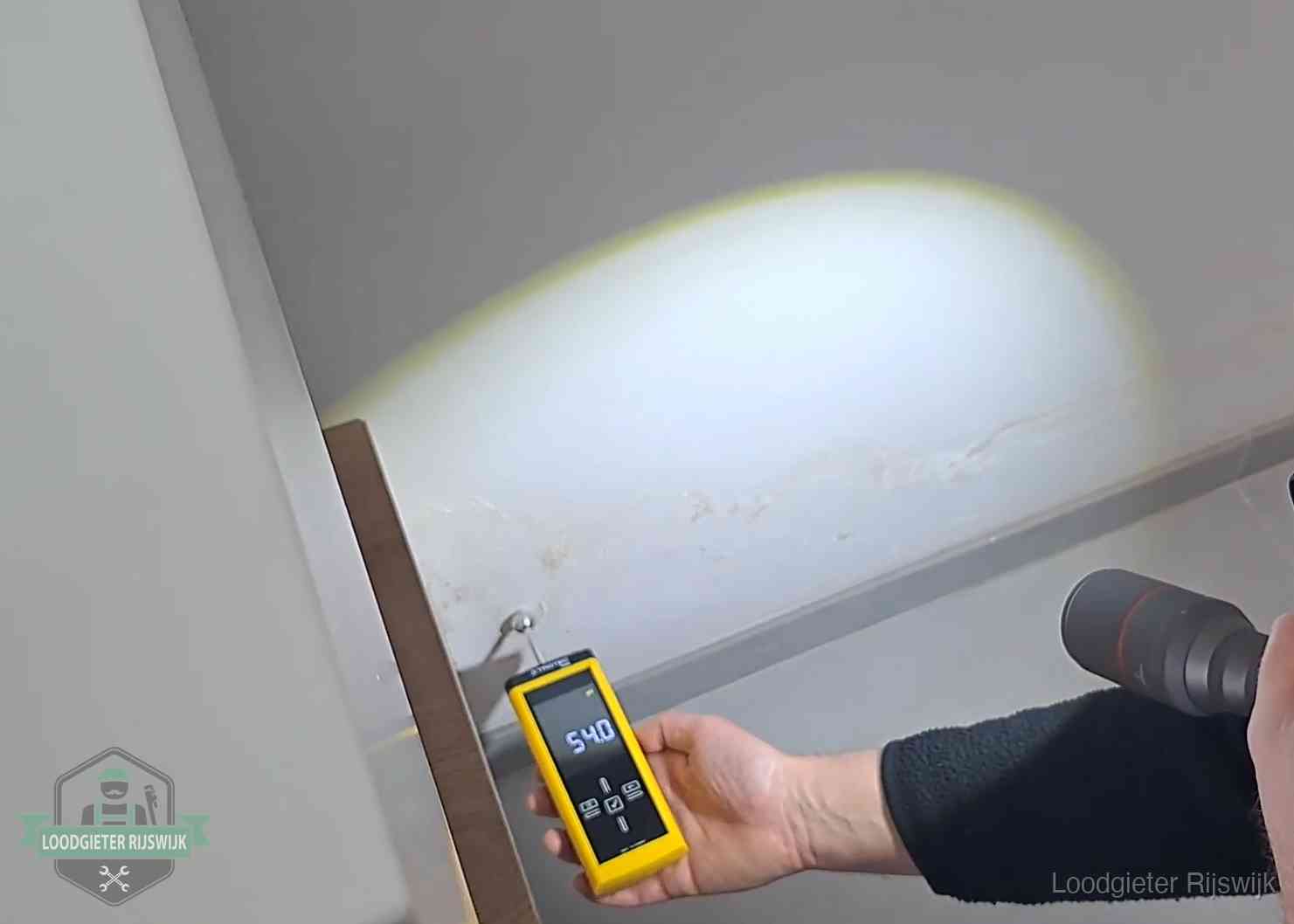 Vochtmeter tegen een natte wand met lekkagesporen in Rijswijk