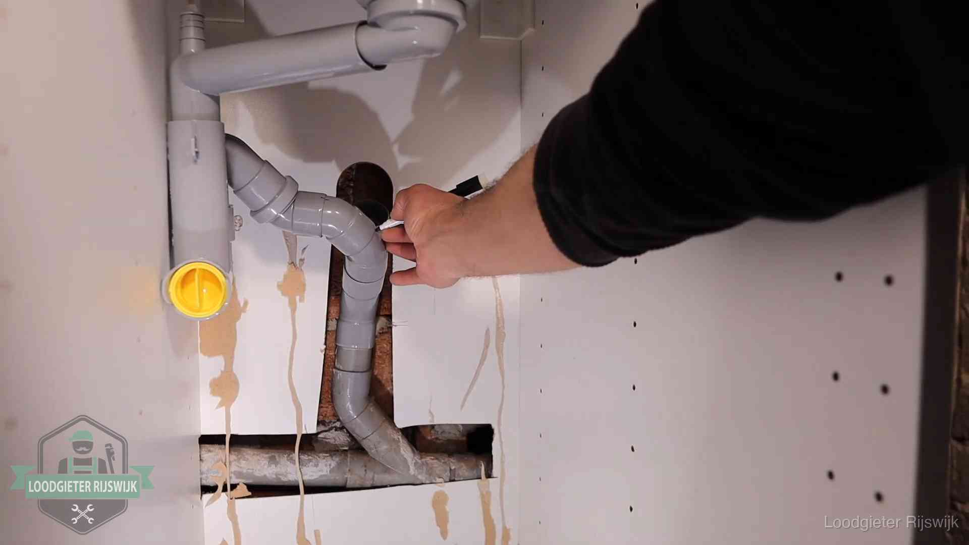 Loodgieter markeert een pvc-afvoerbuis onder een gootsteen in Rijswijk