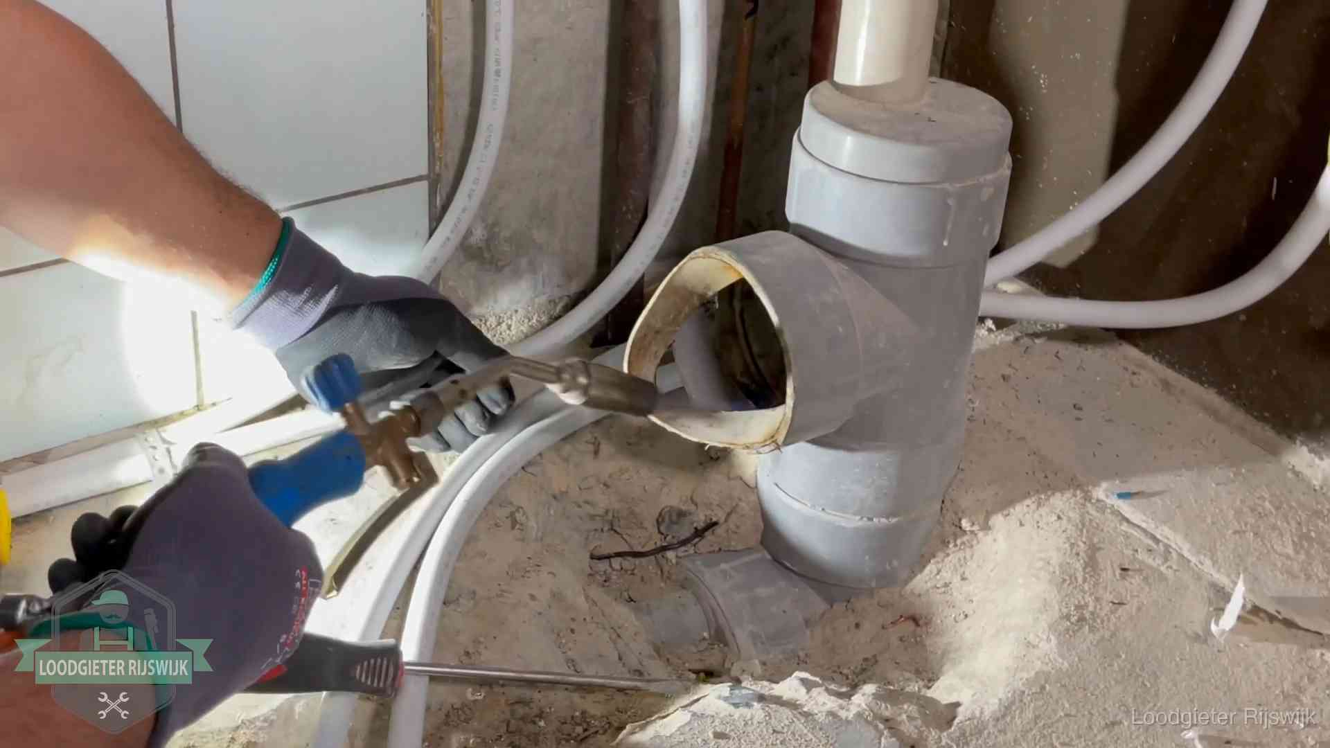 Loodgieter werkt met brander en messing kraanwerk aan leidingen in Rijswijk