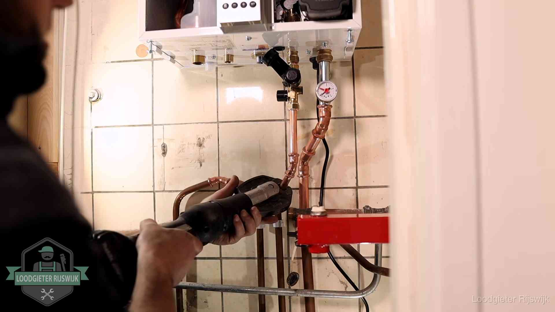 Monteur werkt aan de leidingen onder een cv-ketel in Rijswijk