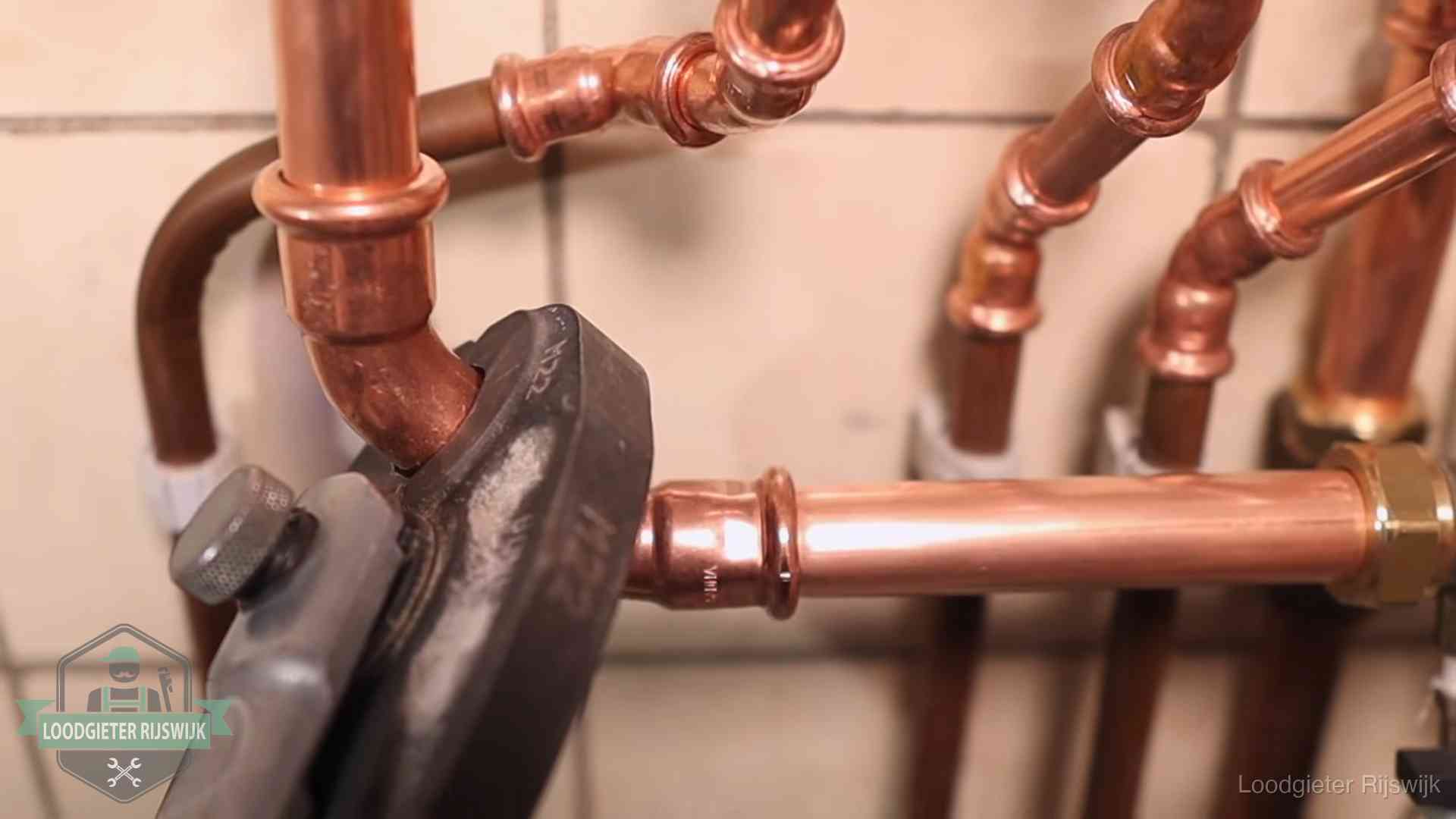 Persmachine perst een koperen fitting op nieuw leidingwerk in Rijswijk