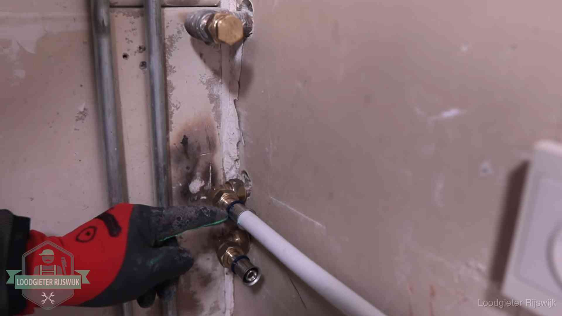 Loodgieter wijst de persfitting op nieuwe muuraansluitingen aan in een woning in Rijswijk