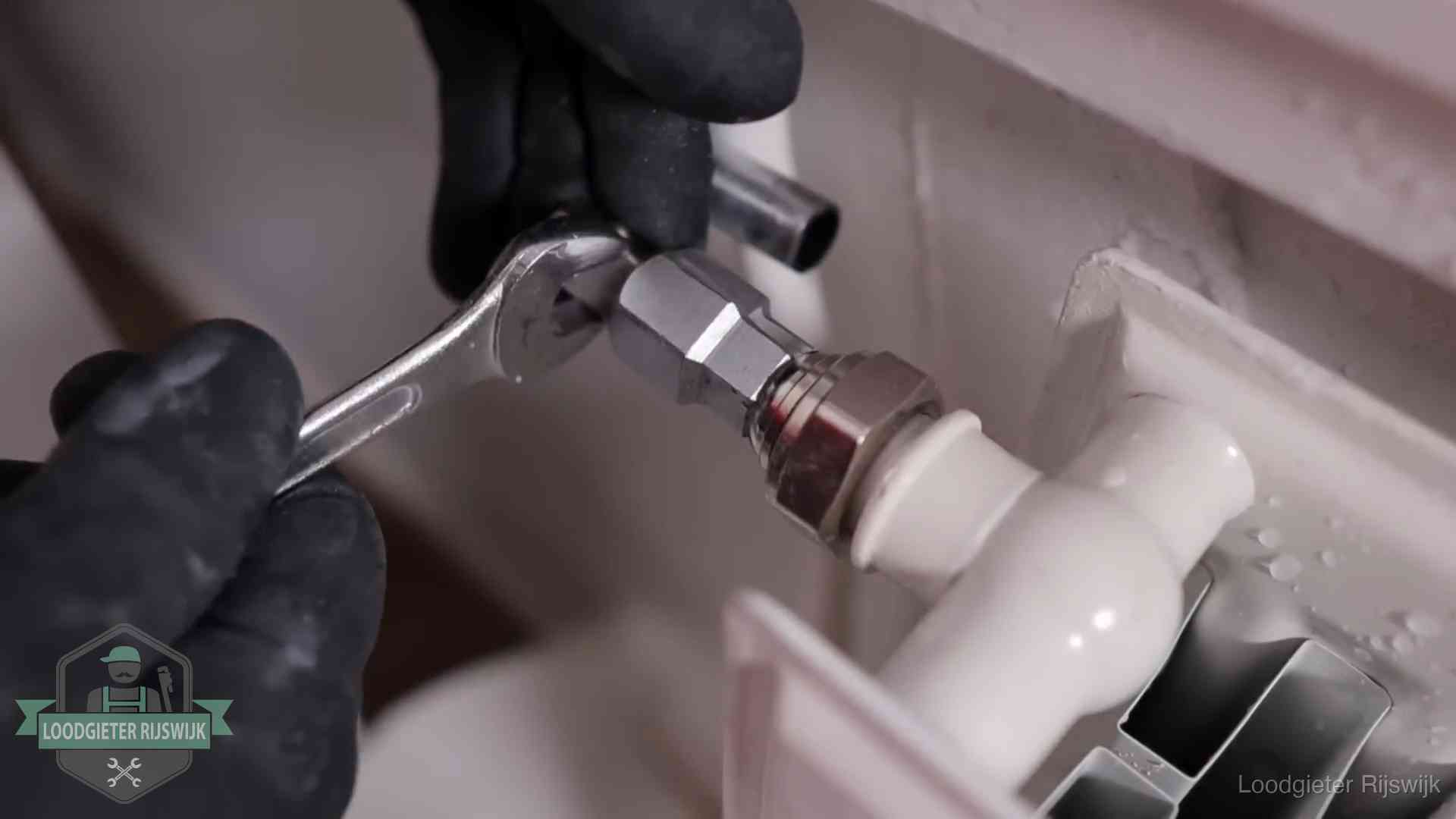 Steeksleutel draait een wartelkoppeling op een radiatorkraan aan in Rijswijk