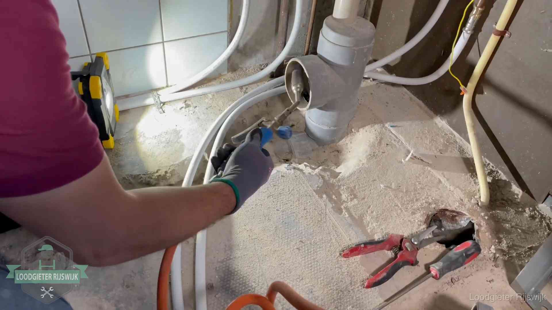 Loodgieter werkt aan leidingen bij een pvc-standleiding in een appartement in Rijswijk