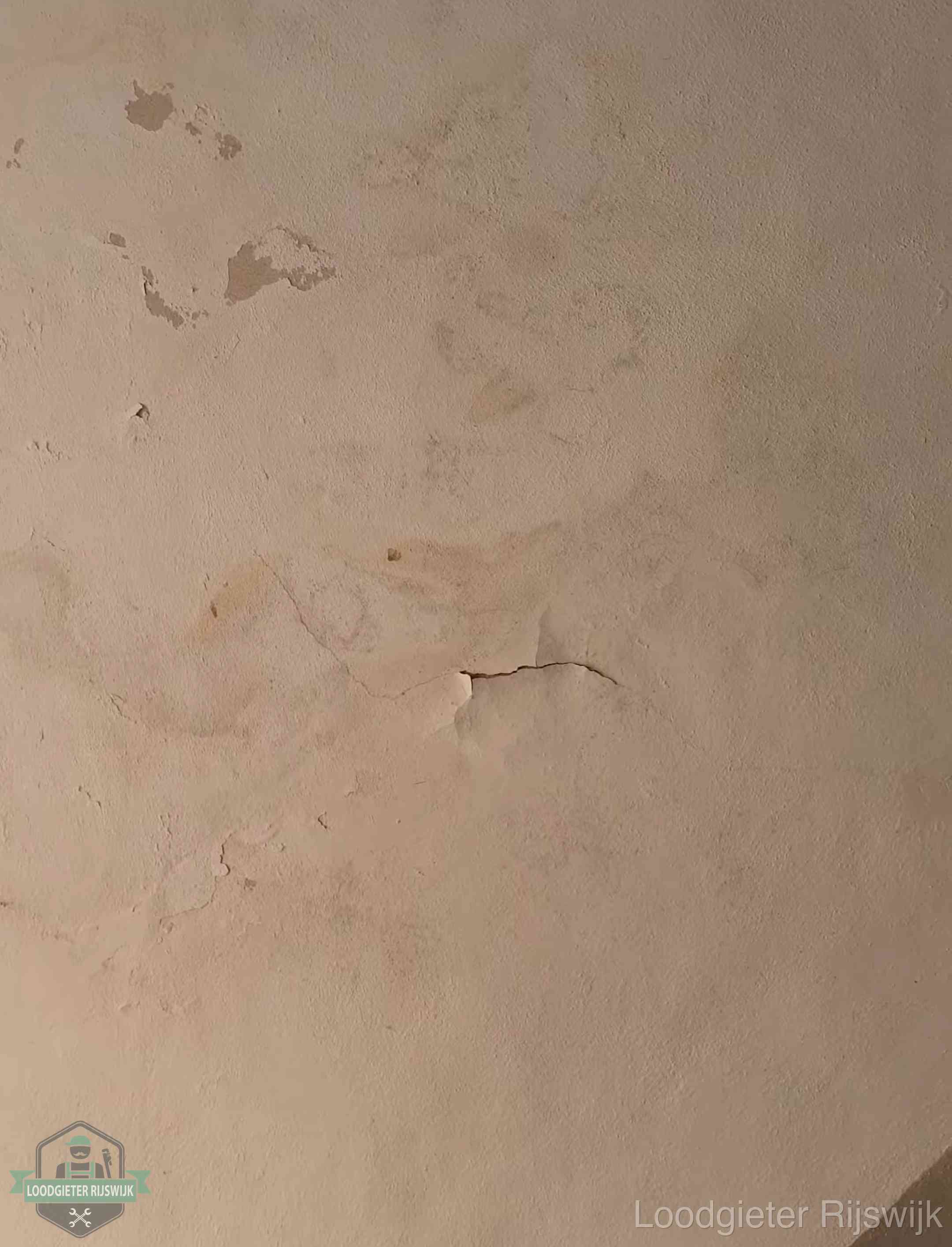Vochtkringen en afbladderende verf op een plafond in Rijswijk, schade voor het meetrapport en de verzekering